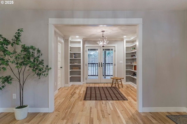 entrance foyer featuring ornamental molding, a chandelier, baseboards, and wood finished floors