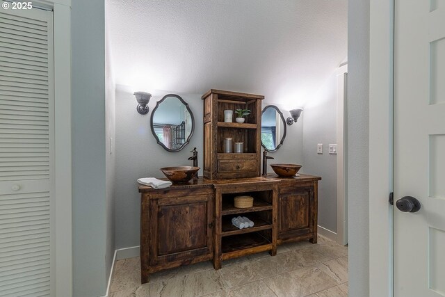 bathroom featuring double vanity, a sink, and baseboards