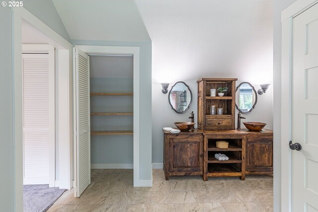 interior space with lofted ceiling, a sink, and baseboards