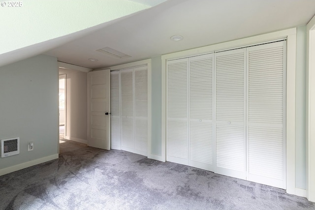unfurnished bedroom with carpet, two closets, lofted ceiling, visible vents, and baseboards