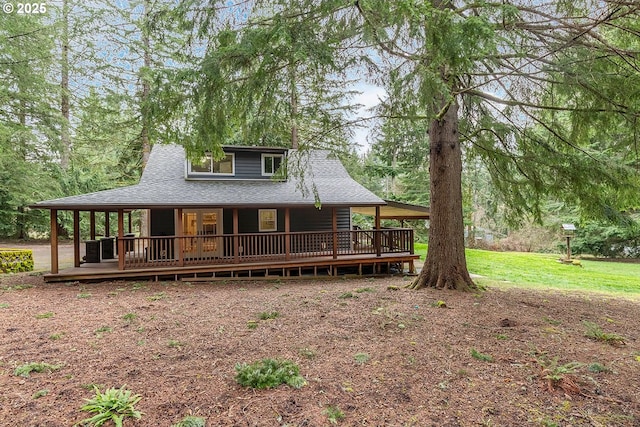 rear view of property featuring a shingled roof, a yard, and a deck