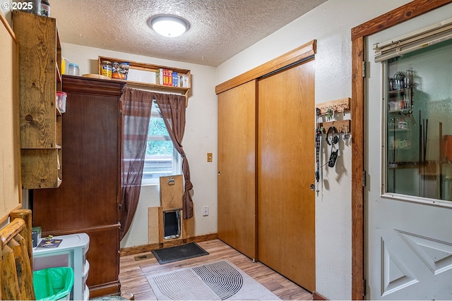 entrance foyer featuring a textured ceiling, light wood-type flooring, and baseboards