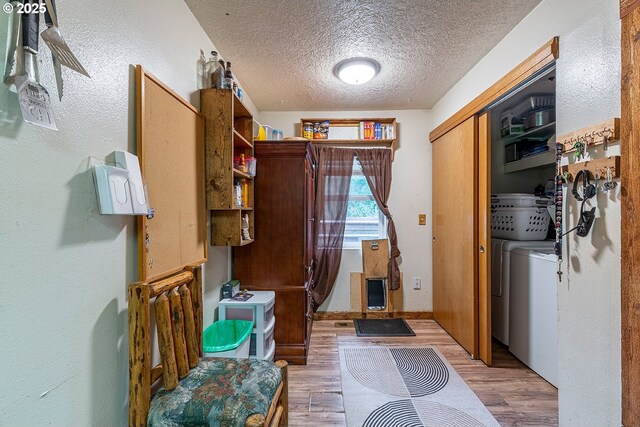 interior space featuring a textured ceiling, washing machine and dryer, and light wood-style flooring