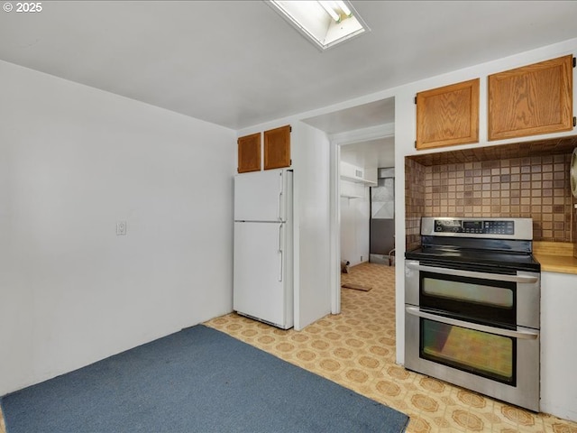 kitchen featuring light countertops, brown cabinetry, freestanding refrigerator, range with two ovens, and tasteful backsplash