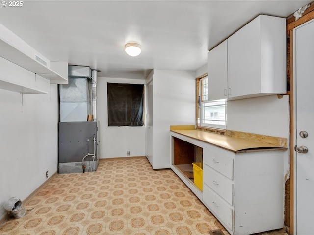 kitchen with visible vents, open shelves, heating unit, light countertops, and white cabinetry
