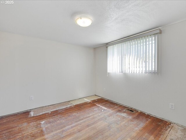 empty room featuring wood-type flooring and visible vents