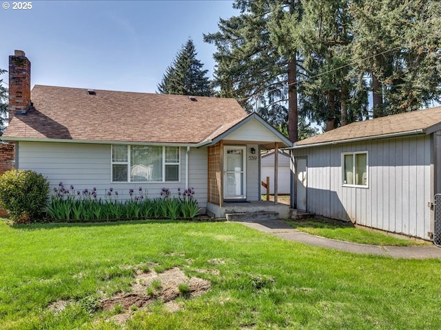 ranch-style home with a front lawn, an outbuilding, and a chimney