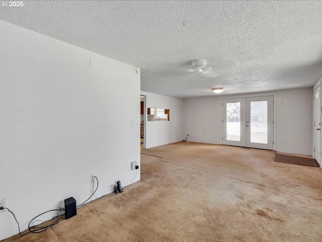 unfurnished living room featuring ceiling fan, french doors, a textured ceiling, and light colored carpet