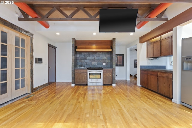 kitchen with stainless steel electric range oven, light wood finished floors, decorative backsplash, baseboards, and dark countertops