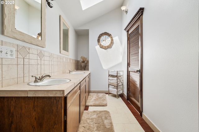 bathroom featuring a skylight, tile patterned floors, lofted ceiling, tasteful backsplash, and double vanity