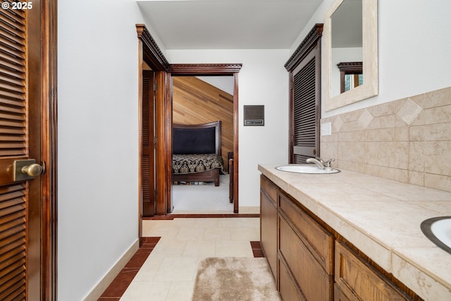bathroom featuring double vanity, ensuite bathroom, and baseboards