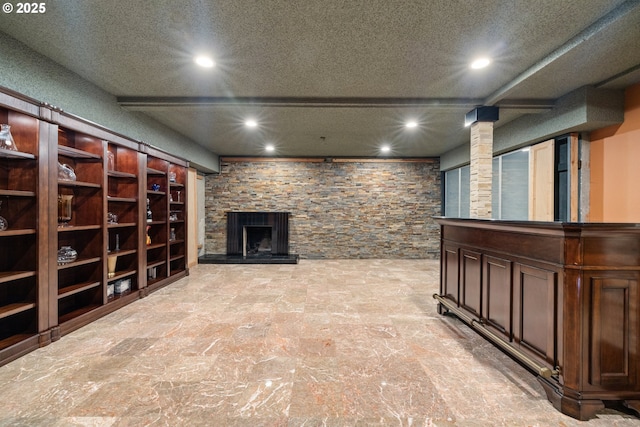 below grade area with recessed lighting, a stone fireplace, and a textured ceiling