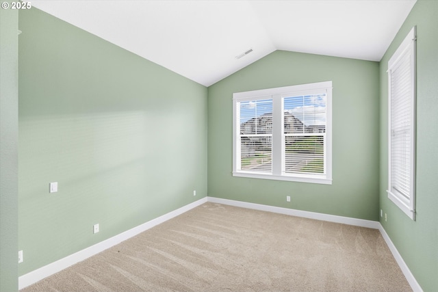 carpeted spare room featuring vaulted ceiling