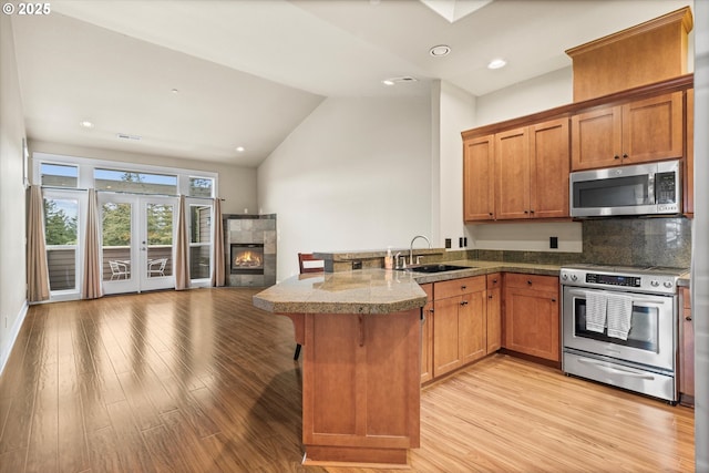 kitchen featuring sink, a fireplace, stainless steel appliances, and kitchen peninsula