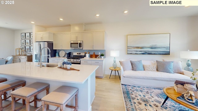 kitchen featuring stainless steel appliances, sink, a kitchen breakfast bar, and an island with sink