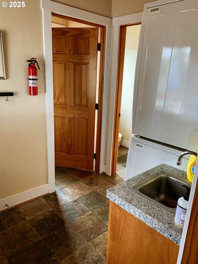 kitchen with sink and stacked washing maching and dryer