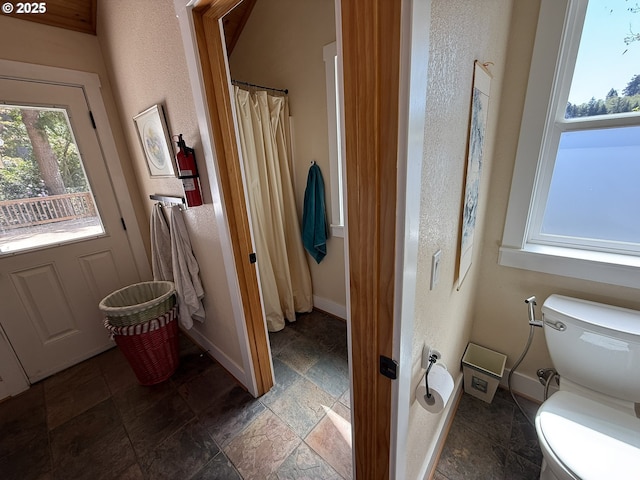 3140 S Tenmile, Lakeside, OR 97449 - full bathroom with stone tile floors, a textured wall, baseboards, and toilet