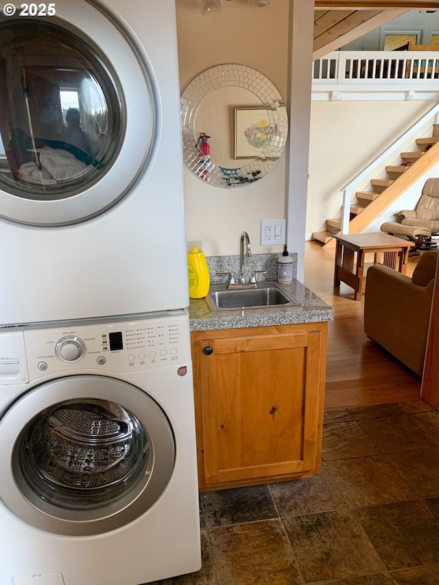 laundry room featuring wet bar, cabinets, and stacked washer and clothes dryer