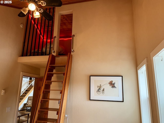 stairs with ceiling fan and a towering ceiling