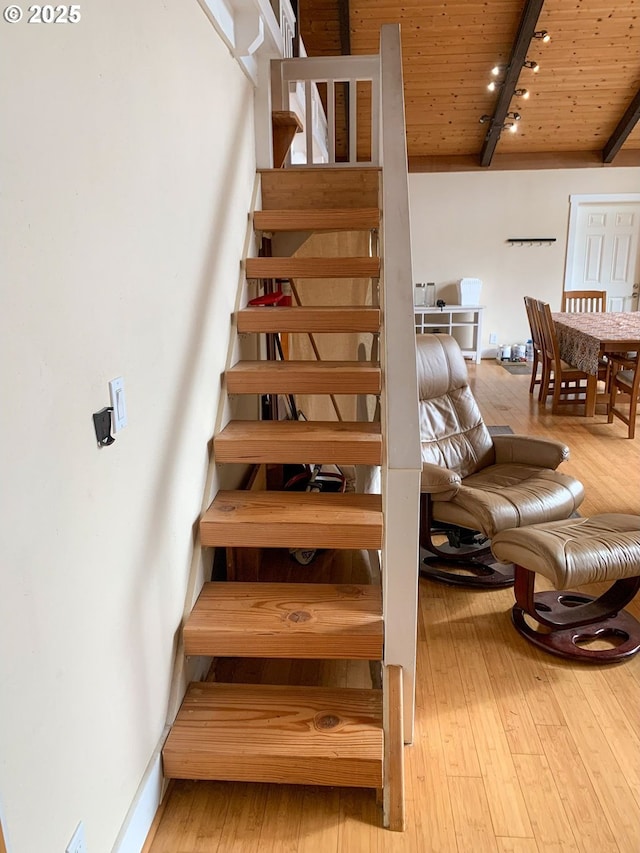 stairs featuring hardwood / wood-style flooring, rail lighting, wooden ceiling, and beam ceiling