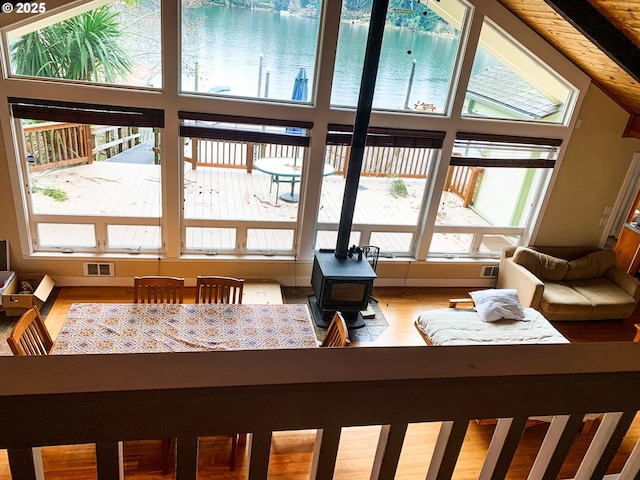 sunroom / solarium featuring a wood stove and a water view