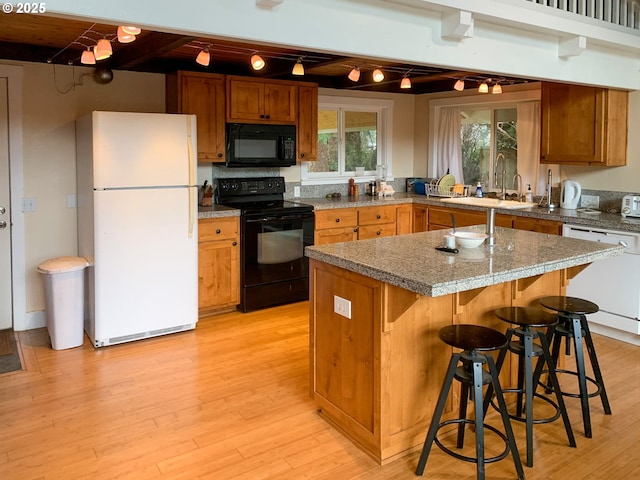 kitchen featuring beam ceiling, a kitchen island, black appliances, sink, and a kitchen breakfast bar