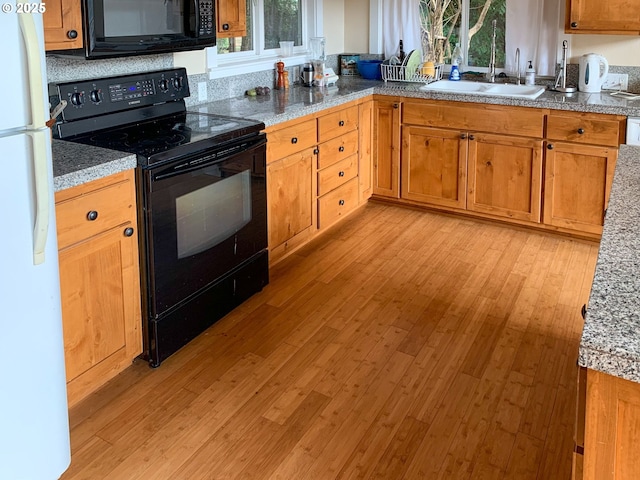 kitchen with sink, black appliances, and light hardwood / wood-style floors