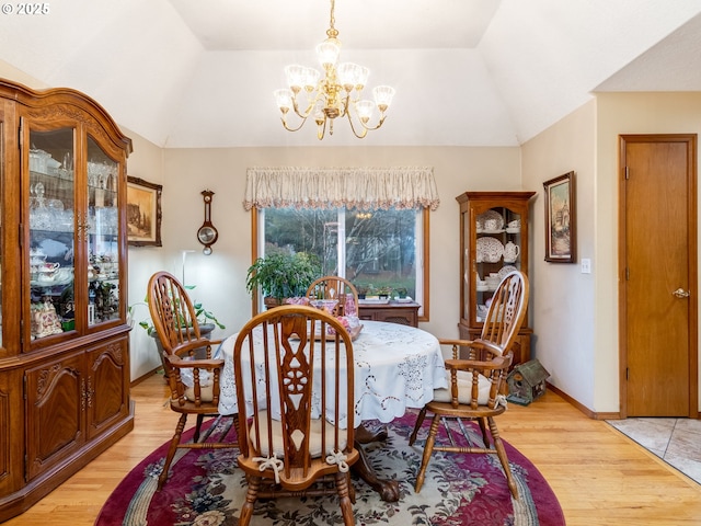 dining area featuring a notable chandelier, light hardwood / wood-style flooring, and vaulted ceiling