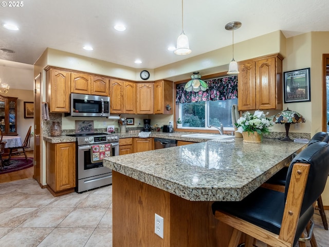 kitchen with decorative light fixtures, light tile patterned flooring, a kitchen bar, kitchen peninsula, and appliances with stainless steel finishes