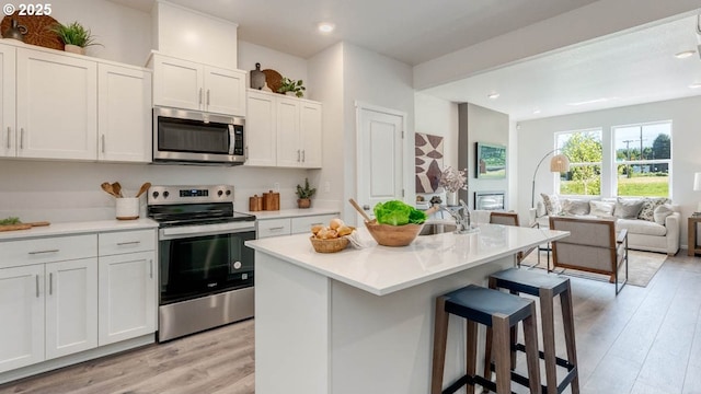 3505 SW Thomas Ave, Gresham, OR 97080 - kitchen with appliances with stainless steel finishes, light wood finished floors, a breakfast bar area, open floor plan, and white cabinetry