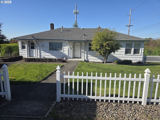 view of front facade with roof with shingles, a chimney, a front lawn, and fence
