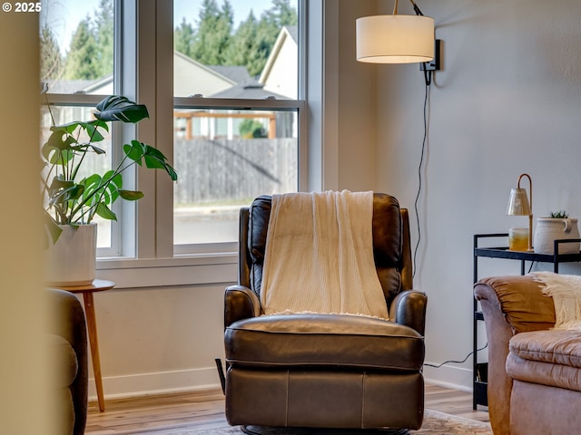 living area with a wealth of natural light, baseboards, and wood finished floors