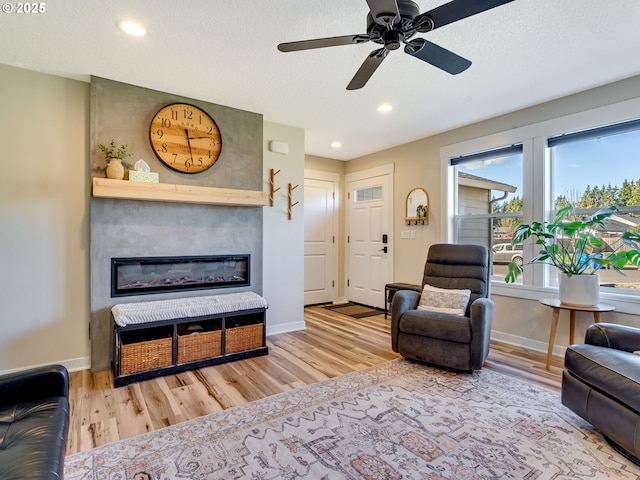 living area with a large fireplace, baseboards, wood finished floors, and recessed lighting