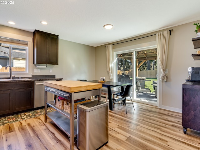 kitchen featuring dark brown cabinetry, baseboards, light wood-style floors, and a sink