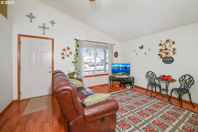 living area with baseboards, lofted ceiling, and wood finished floors