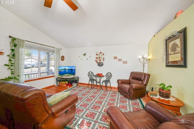 living area featuring ceiling fan, baseboards, wood finished floors, and vaulted ceiling