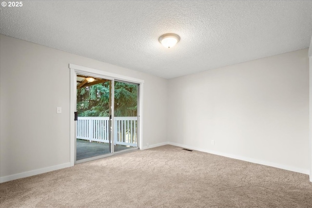 carpeted spare room with baseboards, visible vents, and a textured ceiling