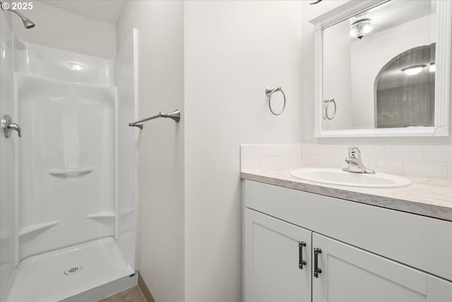 bathroom with tasteful backsplash, walk in shower, and vanity