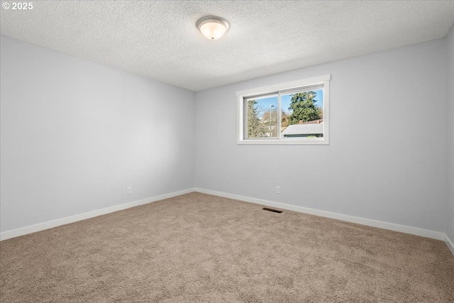 spare room featuring carpet floors, visible vents, a textured ceiling, and baseboards