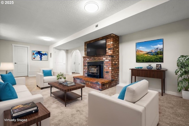 living room with a textured ceiling, baseboards, arched walkways, and light colored carpet