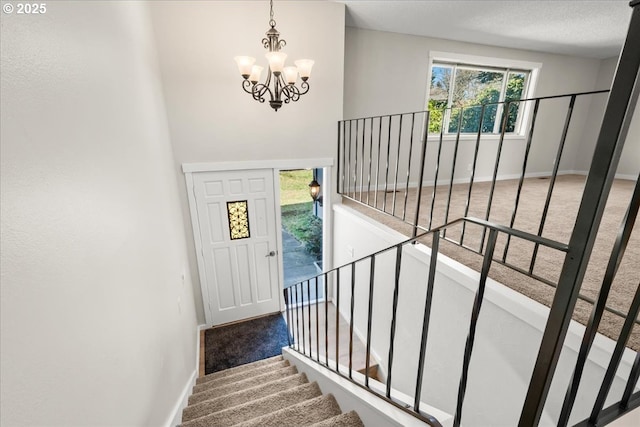 staircase with a chandelier, carpet flooring, and baseboards