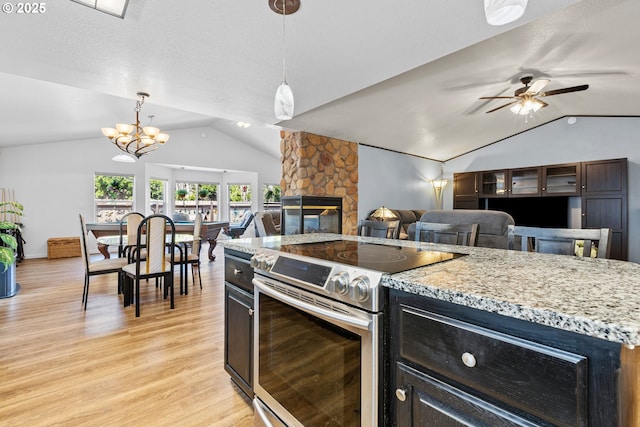 307 Cambridge Dr, Sutherlin, OR 97479 - kitchen featuring stainless steel range with electric cooktop, vaulted ceiling, a stone fireplace, light wood-style floors, and a chandelier