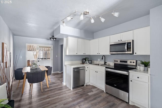 kitchen featuring appliances with stainless steel finishes, sink, white cabinets, dark wood-type flooring, and a textured ceiling