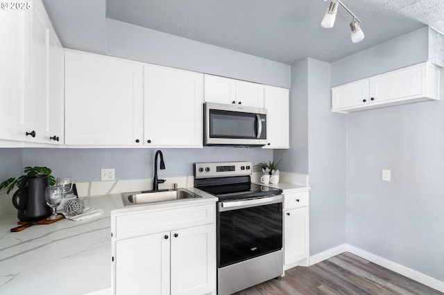 kitchen with white cabinetry, appliances with stainless steel finishes, sink, and light stone counters