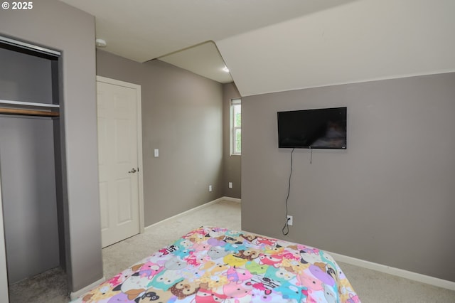 carpeted bedroom with baseboards, lofted ceiling, and a closet