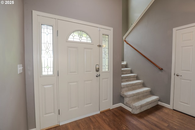 foyer entrance with dark wood-type flooring, baseboards, and stairway