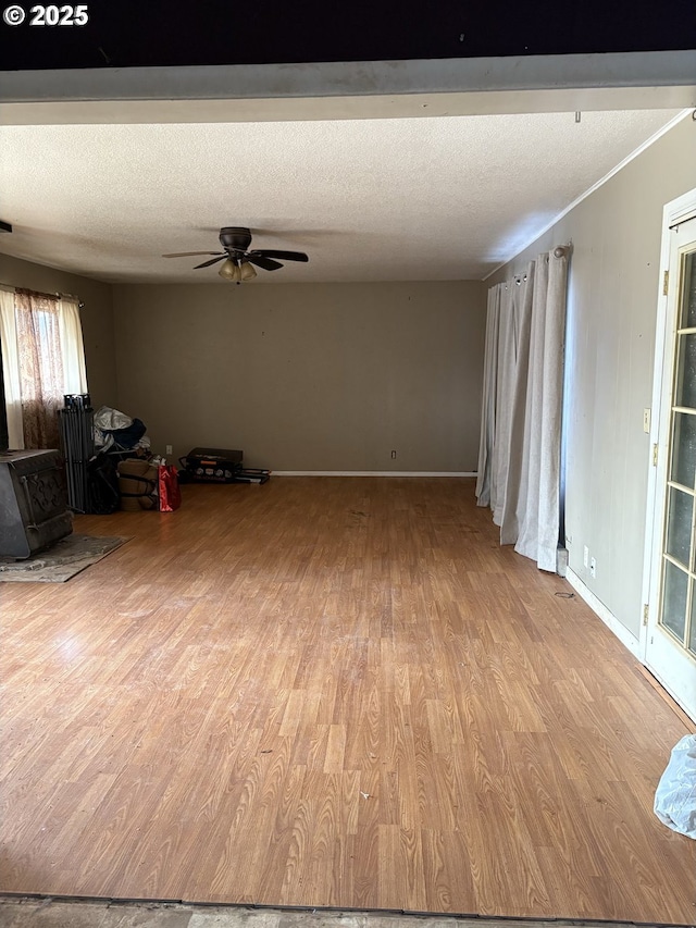 unfurnished living room featuring a textured ceiling, ceiling fan, and light hardwood / wood-style flooring