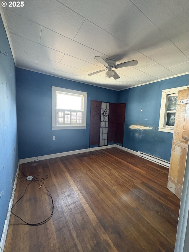 unfurnished room featuring dark hardwood / wood-style flooring, ceiling fan, and a baseboard radiator