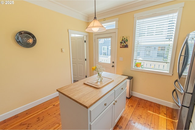 319 Kinnikinnick Way, Depoe Bay, OR 97341 - kitchen featuring freestanding refrigerator, light wood-type flooring, crown molding, white cabinetry, and decorative light fixtures