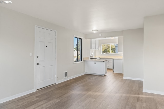 kitchen with kitchen peninsula, white cabinetry, sink, and light wood-type flooring